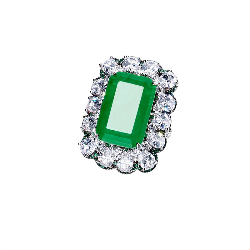 Ring with a green gemstone and diamond-studded halo on a white background