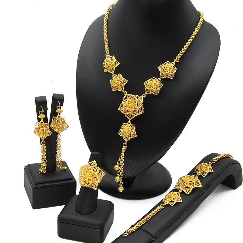 Gold jewelry set including necklace, earrings, and bracelet on black stands against a white background.