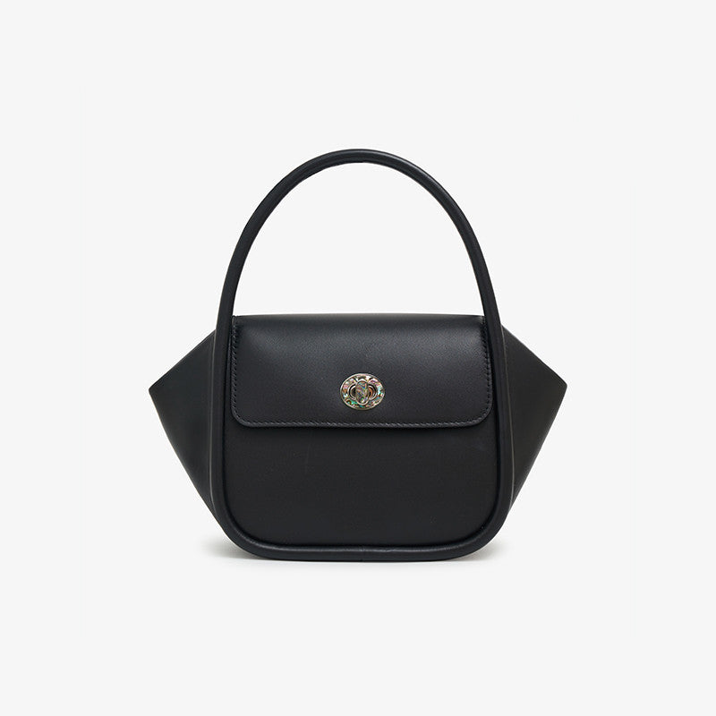 Black handbag with a decorative emblem on a light gray background