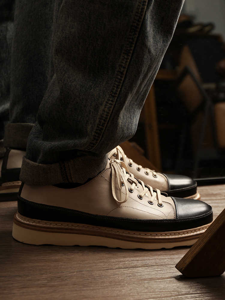 Close-up of a person wearing black and white sneakers on a wooden floor.