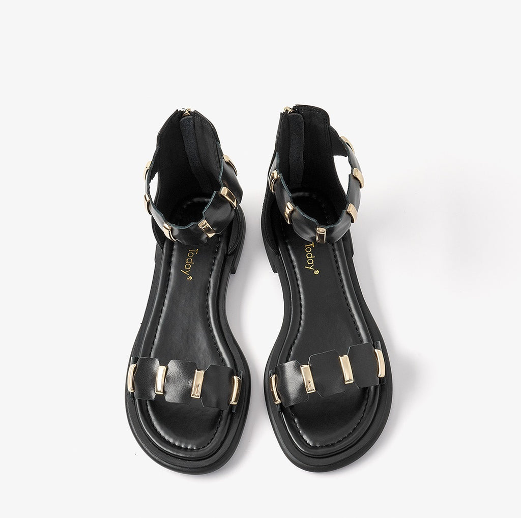 Pair of black sandals with gold accents on a white background