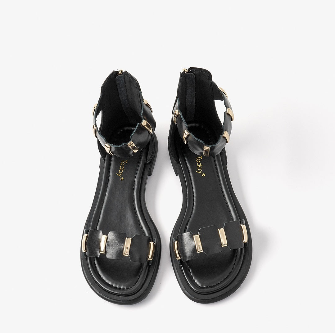 Pair of black sandals with gold accents on a white background