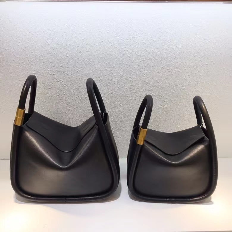 Two black handbags with gold accents on a light gray background