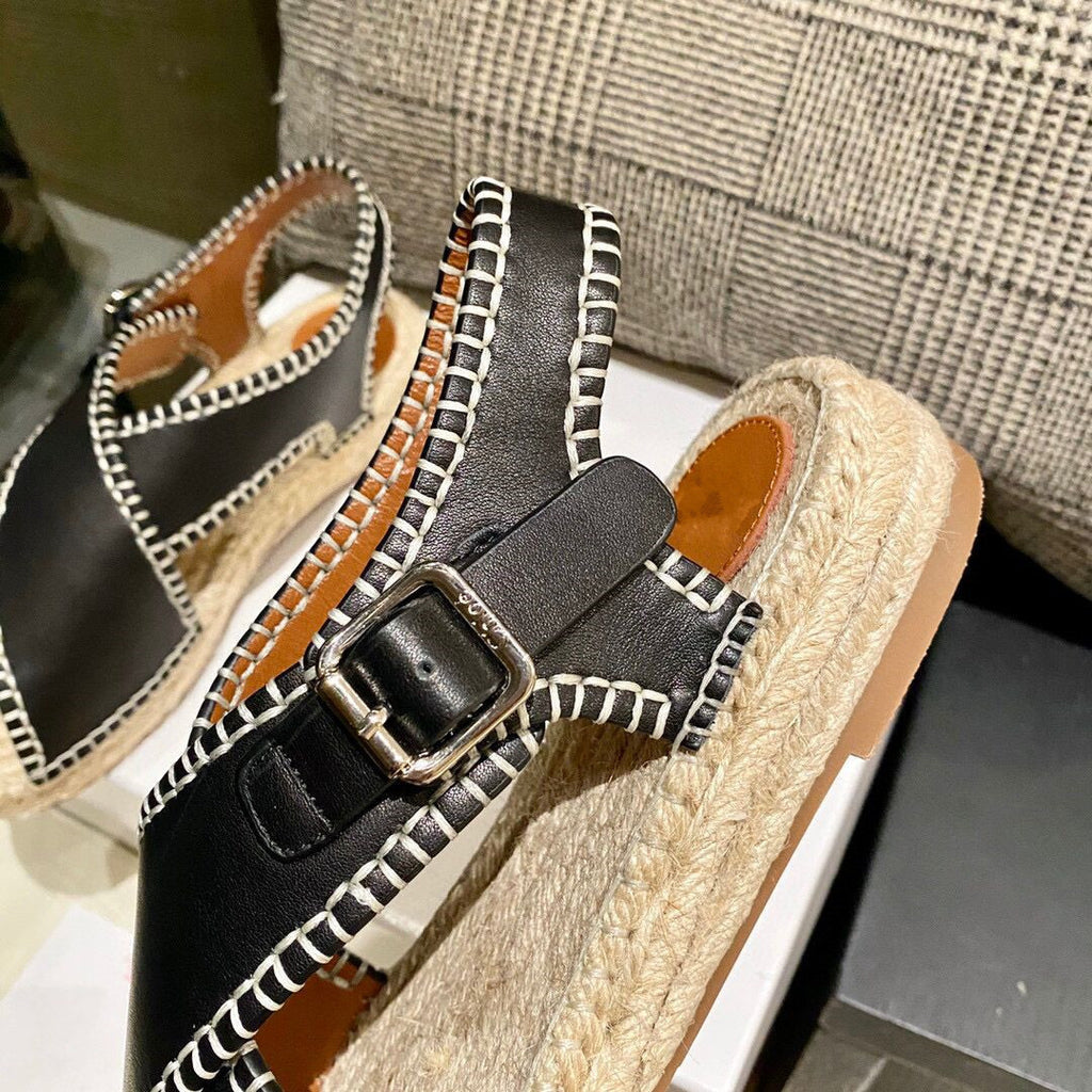 Black espadrille sandals with a buckle on a neutral background
