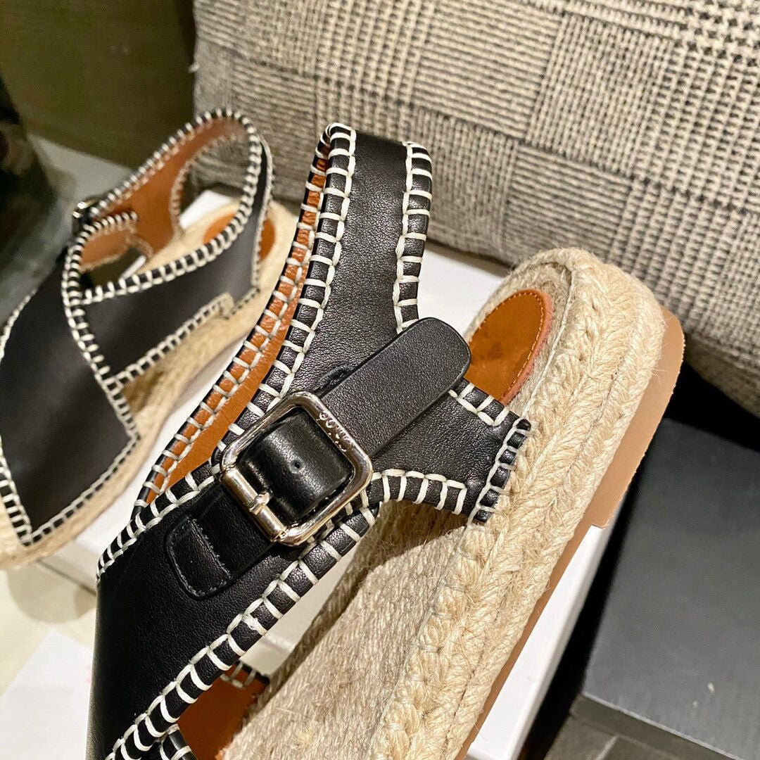 Black espadrille sandals with a buckle on a neutral background