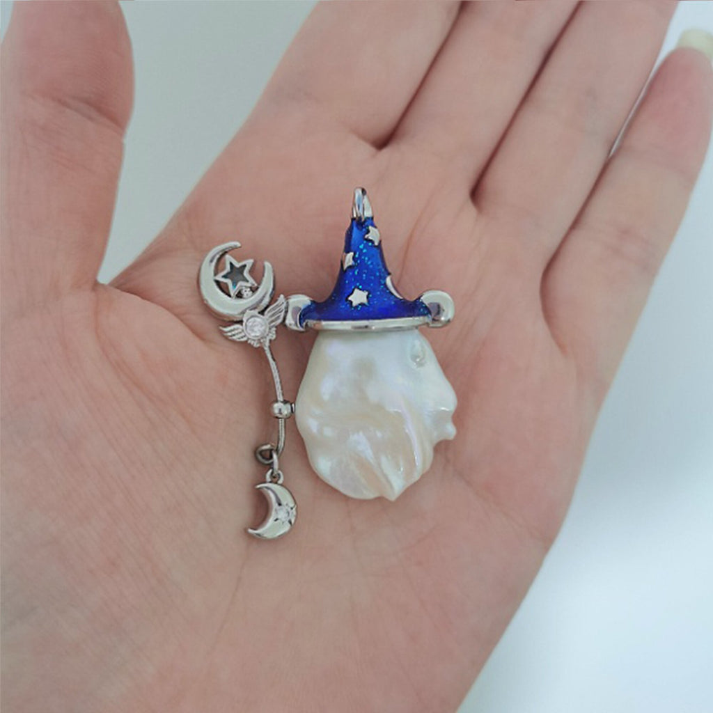 Pendant with wizard hat, moon, and star design held in a hand against a white background