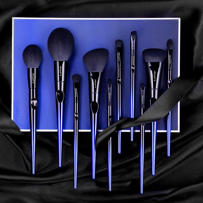 Set of makeup brushes with black handles and silver tips on a blue background
