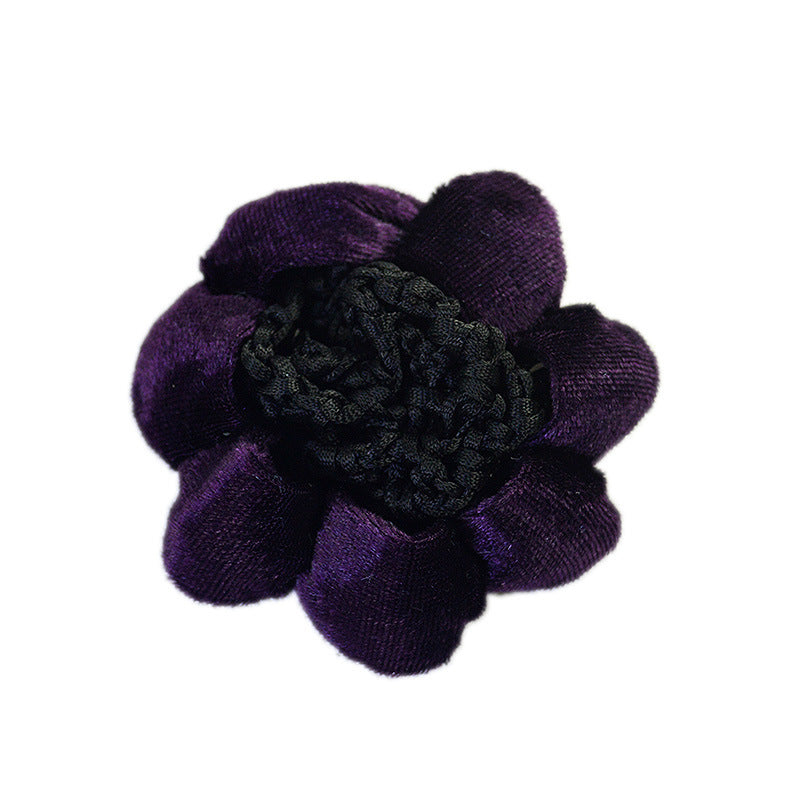 Purple flower-shaped hair clip with a black center on a white background