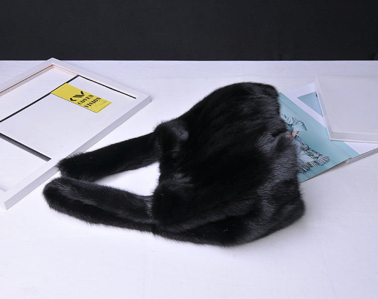 Black fur hat on a white surface with a dark background