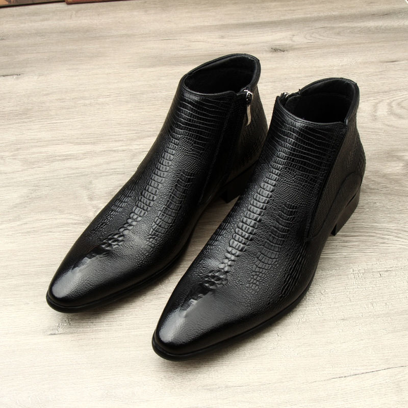 Black leather ankle boots with textured pattern on a light wooden floor.