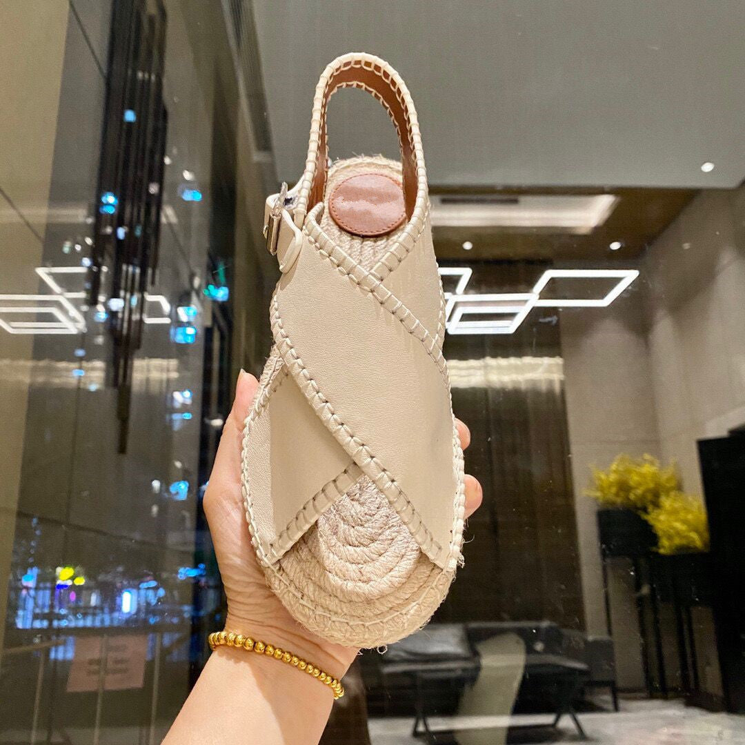 Beige sandal held in a hand with a blurred indoor background