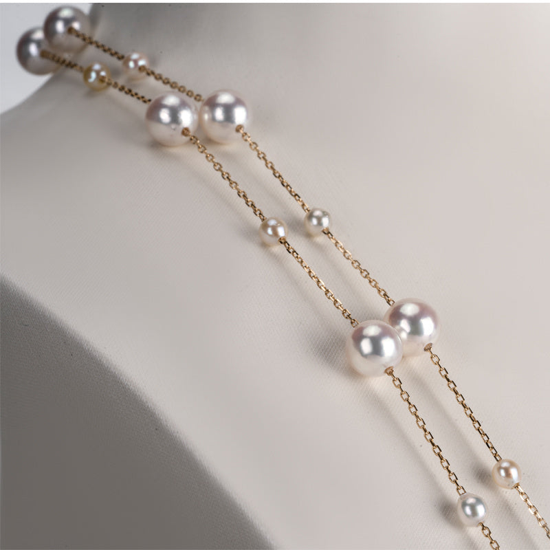 Pearl necklace with gold chain on a mannequin neck against a neutral background