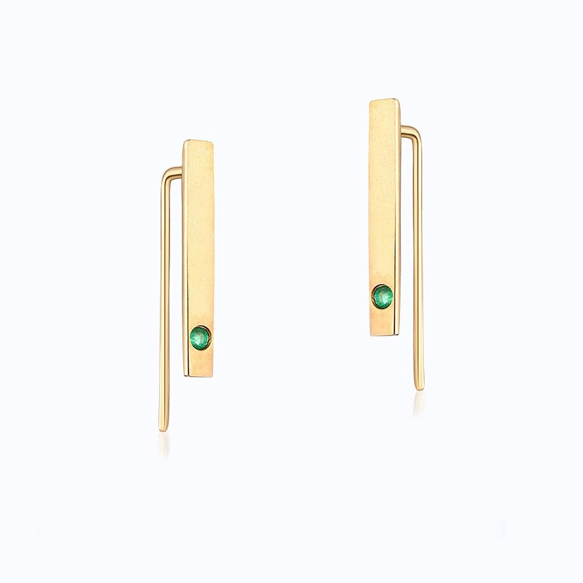 Gold earrings with green gemstones on a white background