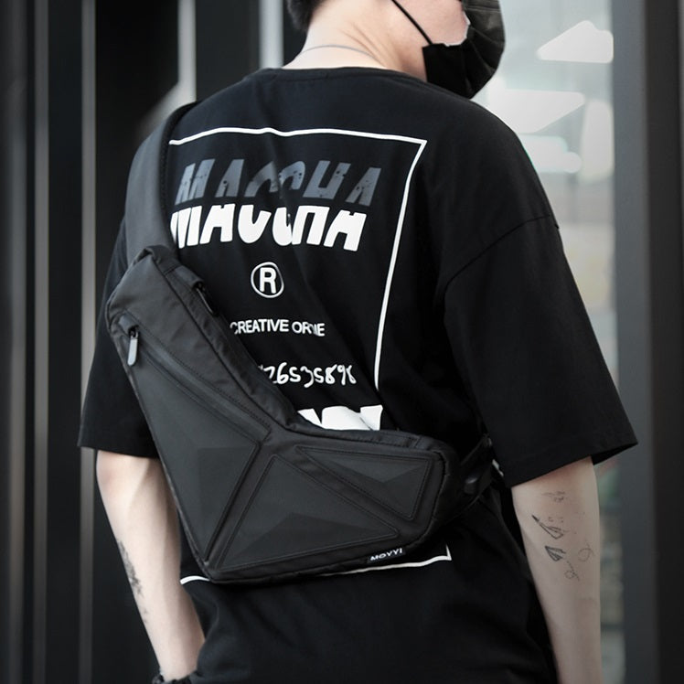Person wearing a black t-shirt with white text and graphics, carrying a black crossbody bag.