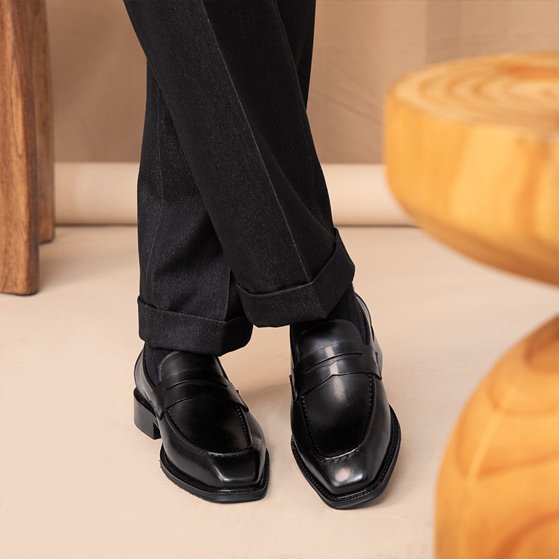 Black dress shoes and pants on a neutral background