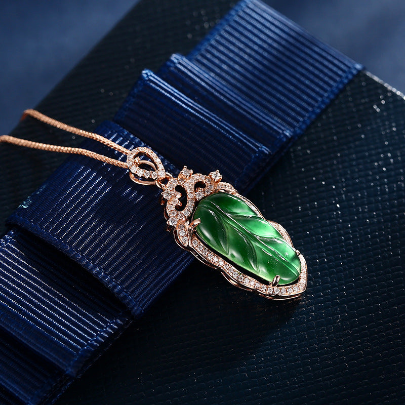 Jewelry pendant with green gemstone and rose gold frame on a blue ribbon
