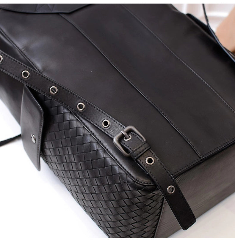 Black leather bag with woven pattern and strap on a white background