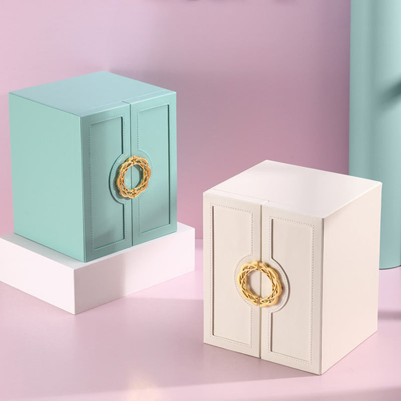 Two jewelry boxes, one green and one white, with gold circular handles on a pink background.