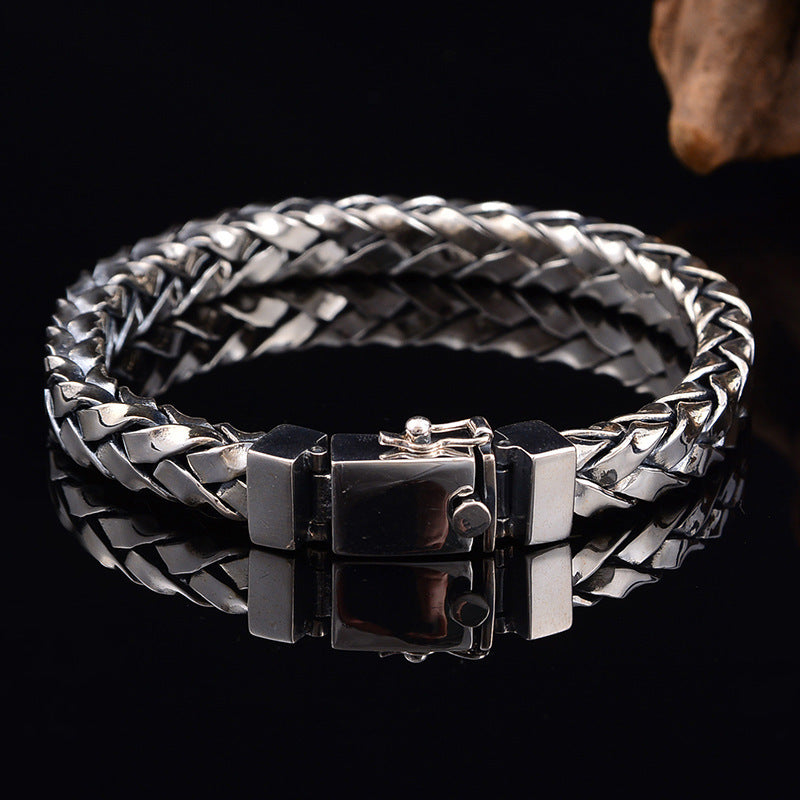 Silver braided bracelet with a clasp on a black background