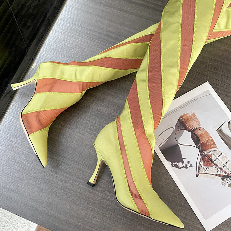 Yellow and orange striped high-heeled shoes on a wooden surface with a magazine in the background.