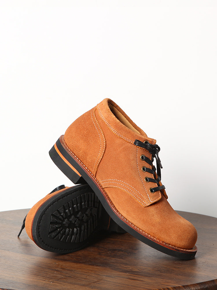 Brown suede shoe with black laces on a wooden surface