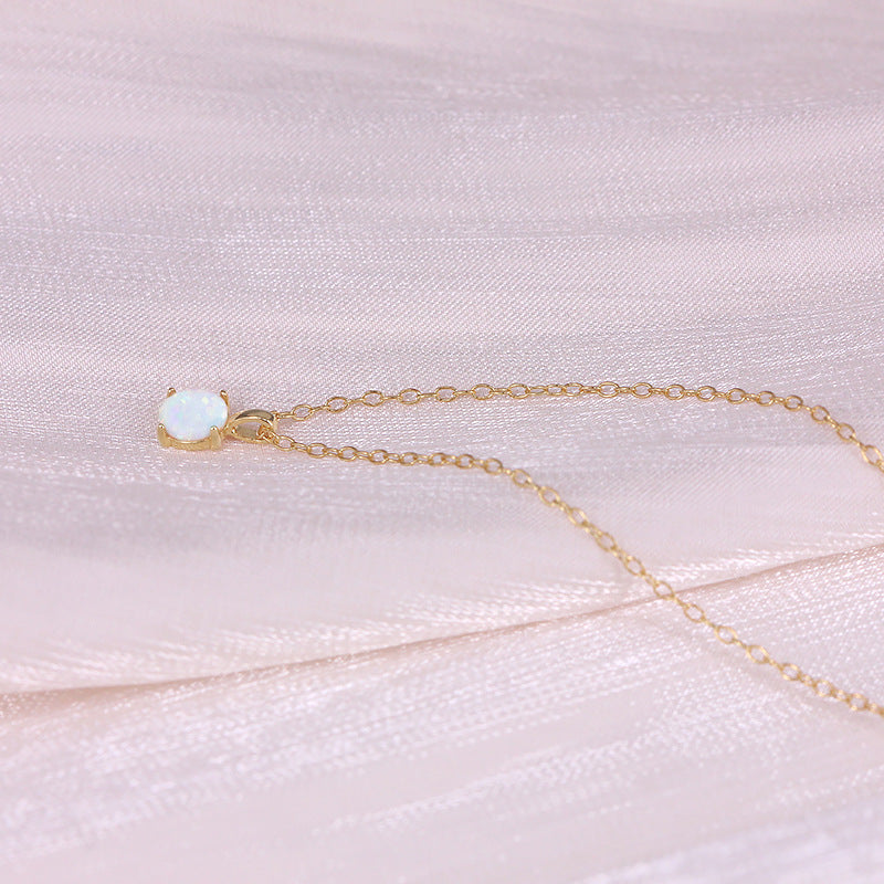 Gold necklace with an opal pendant on a pink fabric background