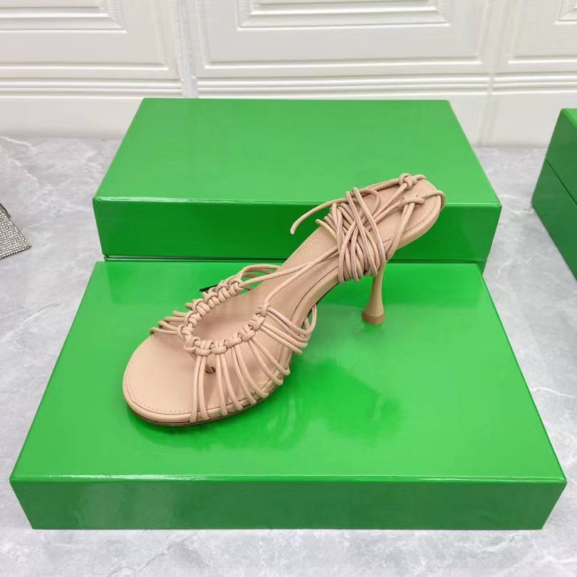 Beige high-heeled shoe on a green platform with a white textured background