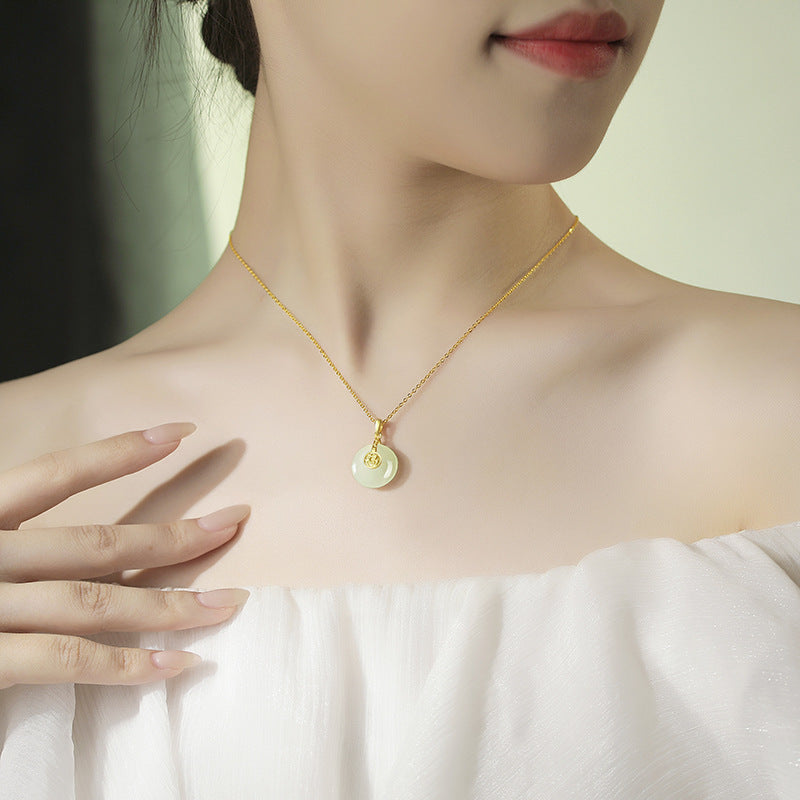 Gold necklace with a pendant worn by a model against a neutral background