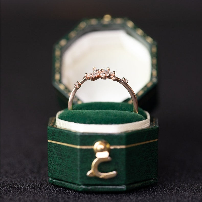 Gold ring with diamonds in a green jewelry box on a dark background