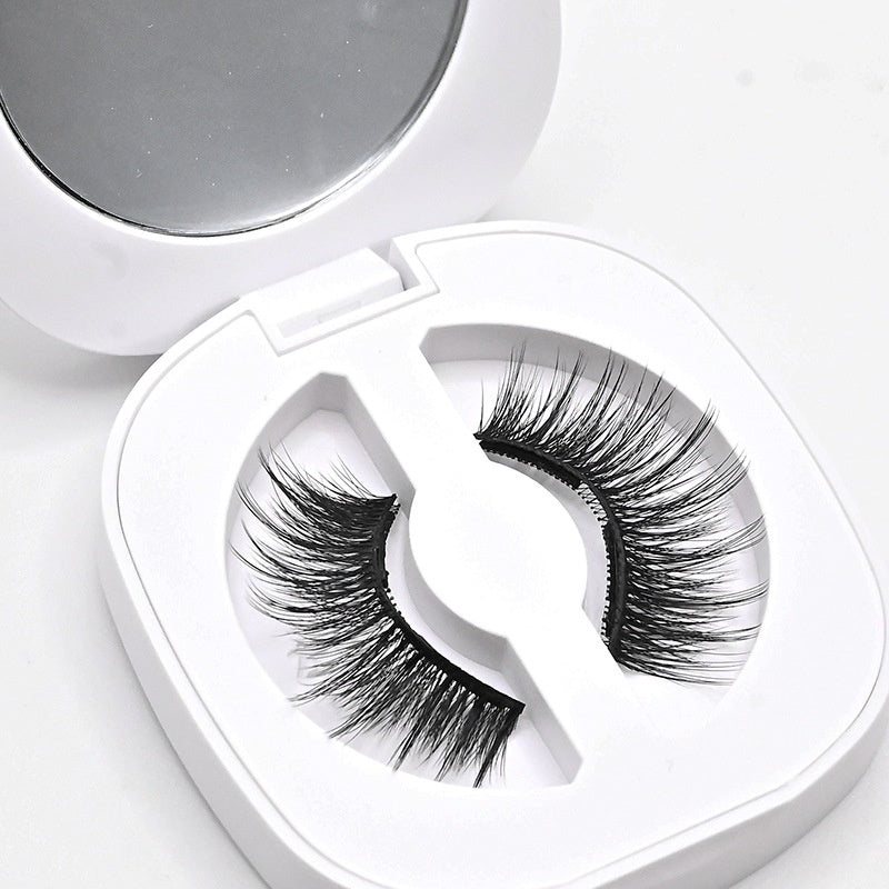 False eyelashes in a heart-shaped white case with a mirror on a light gray background