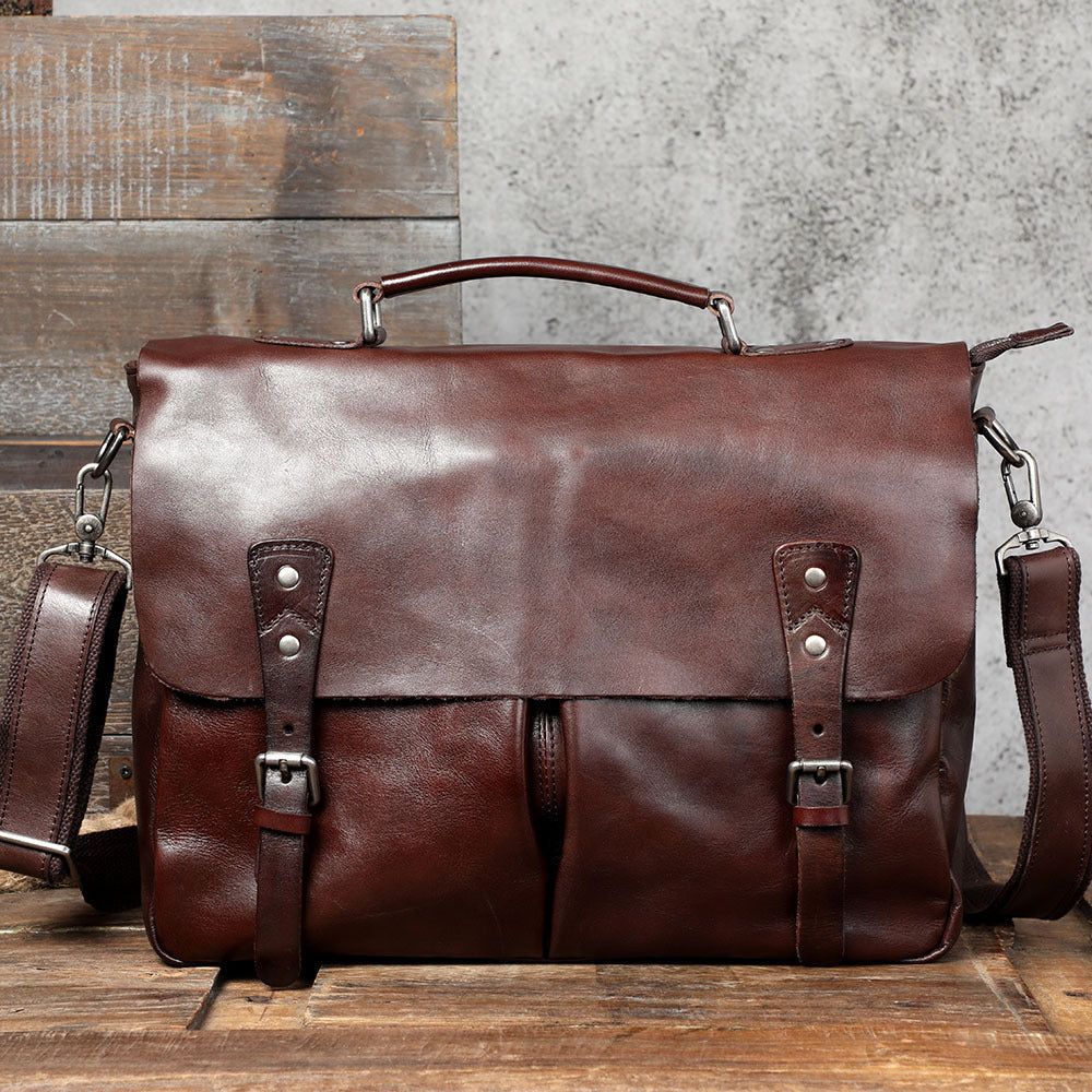 Brown leather briefcase with shoulder strap on a wooden surface