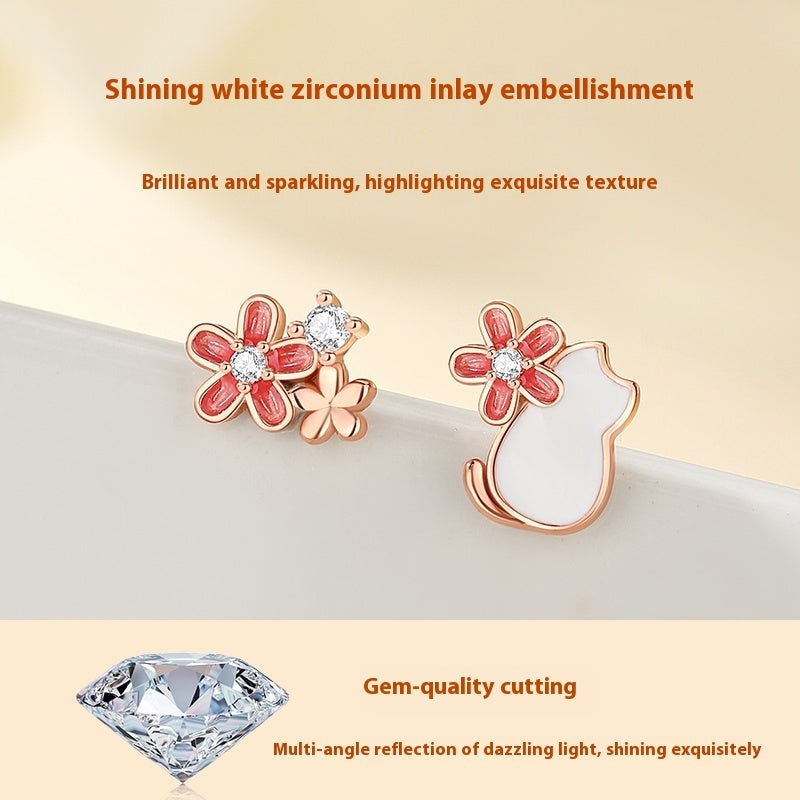 Cat-shaped earrings with red flower details on a beige background