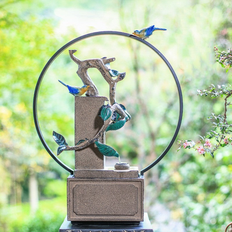 Decorative sculpture with birds on a branch against a blurred green background