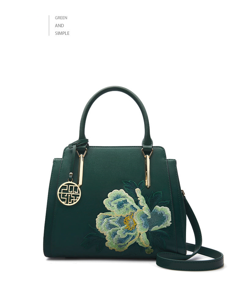 Green handbag with floral embroidery on a white background