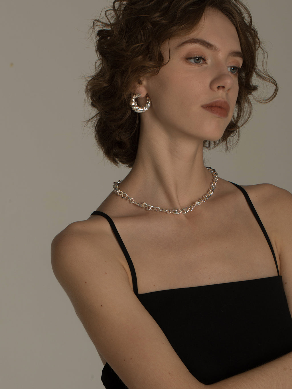 Woman wearing a black top and silver necklace with a neutral background