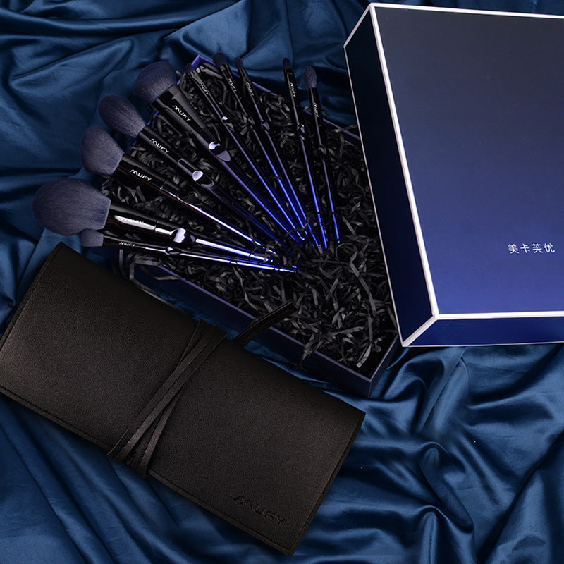 Set of makeup brushes in a box with a black case on a blue fabric background