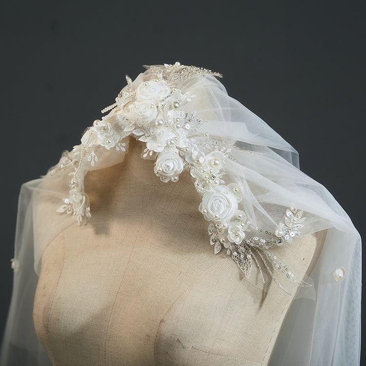 Elegant wedding veil with floral and bead details on a mannequin head against a dark background