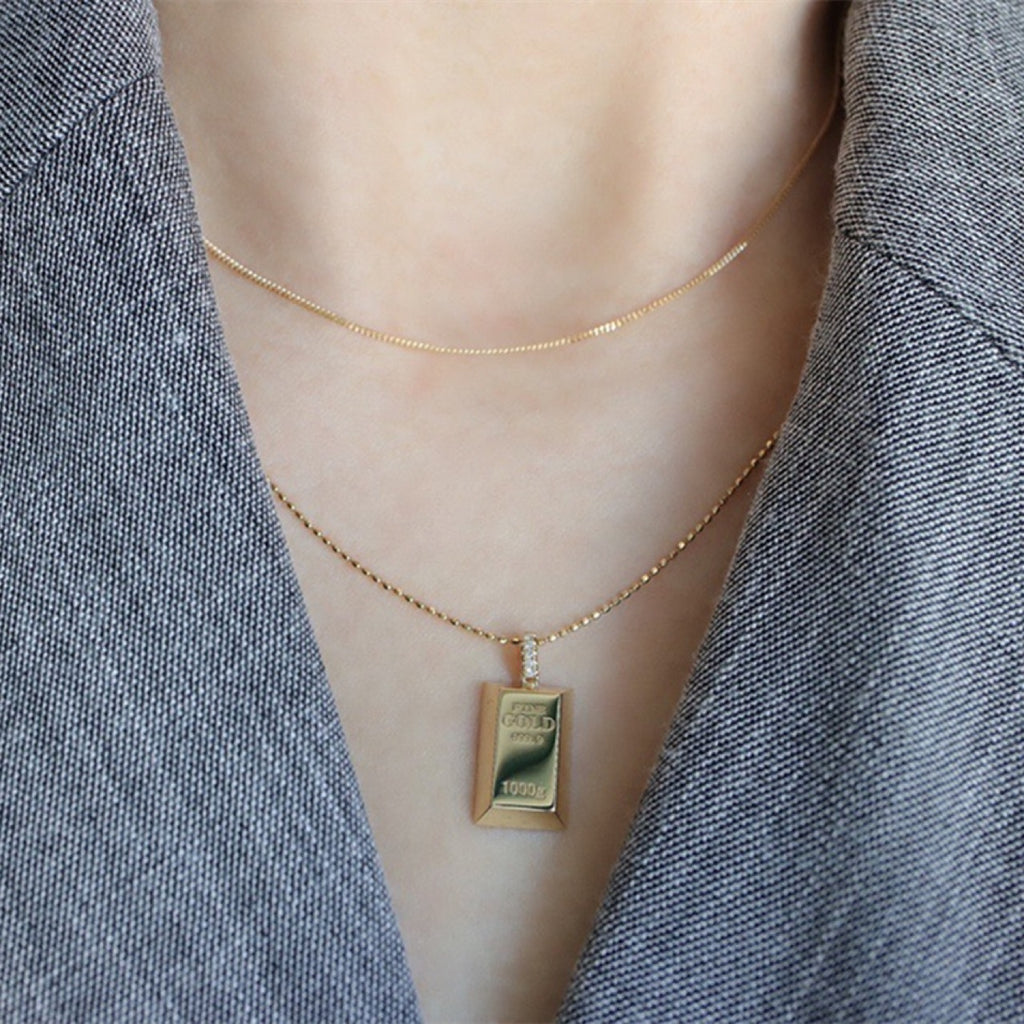 Gold necklace with a gold bar pendant on a mannequin