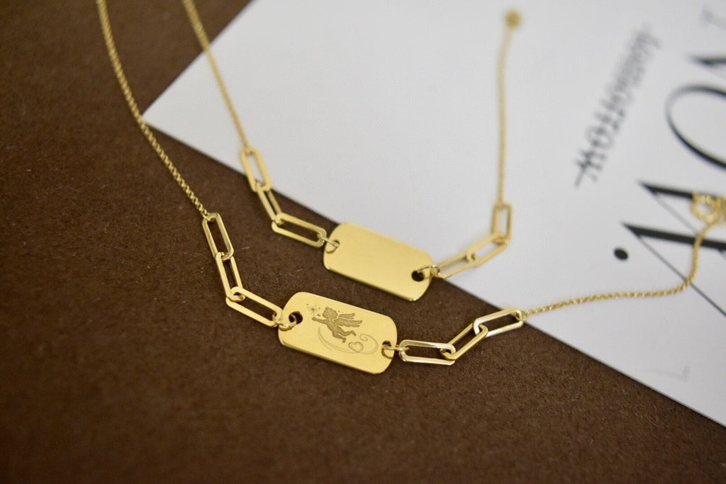 Gold necklaces with engraved tags on a brown surface