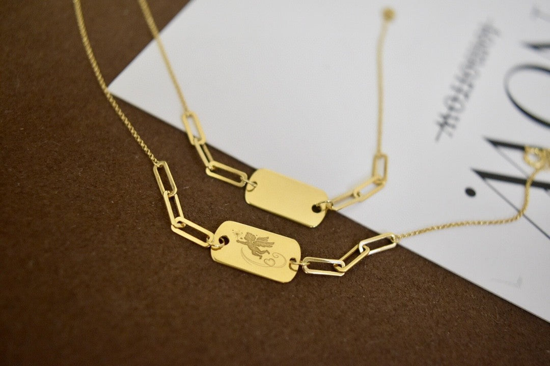Gold necklaces with engraved tags on a brown surface