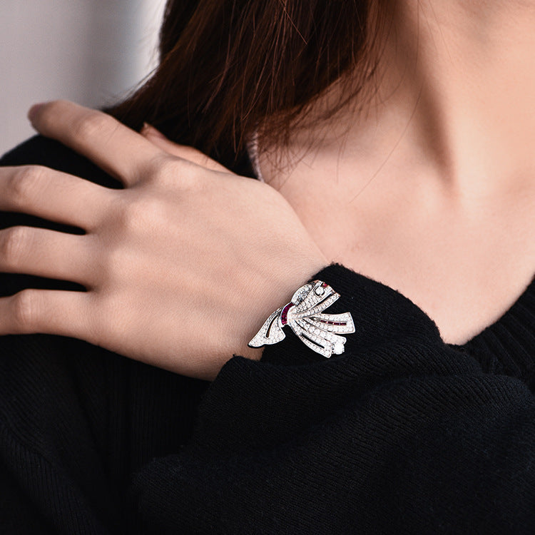 Close-up of a hand wearing a silver bracelet with a bow design.