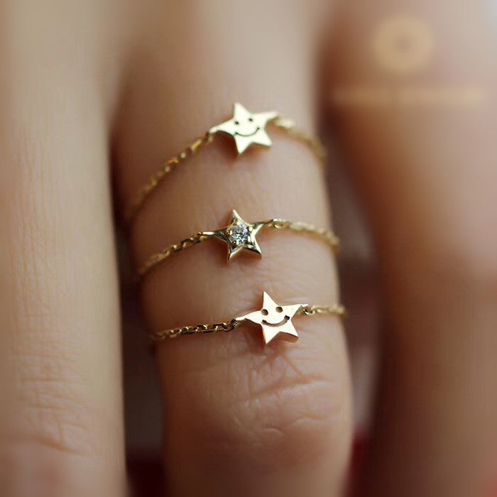 Gold star-shaped rings on a finger with a blurred background