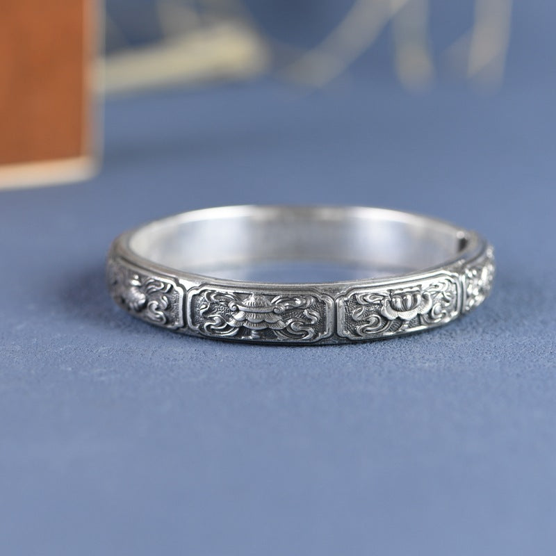 Silver bracelet with intricate designs on a blue background