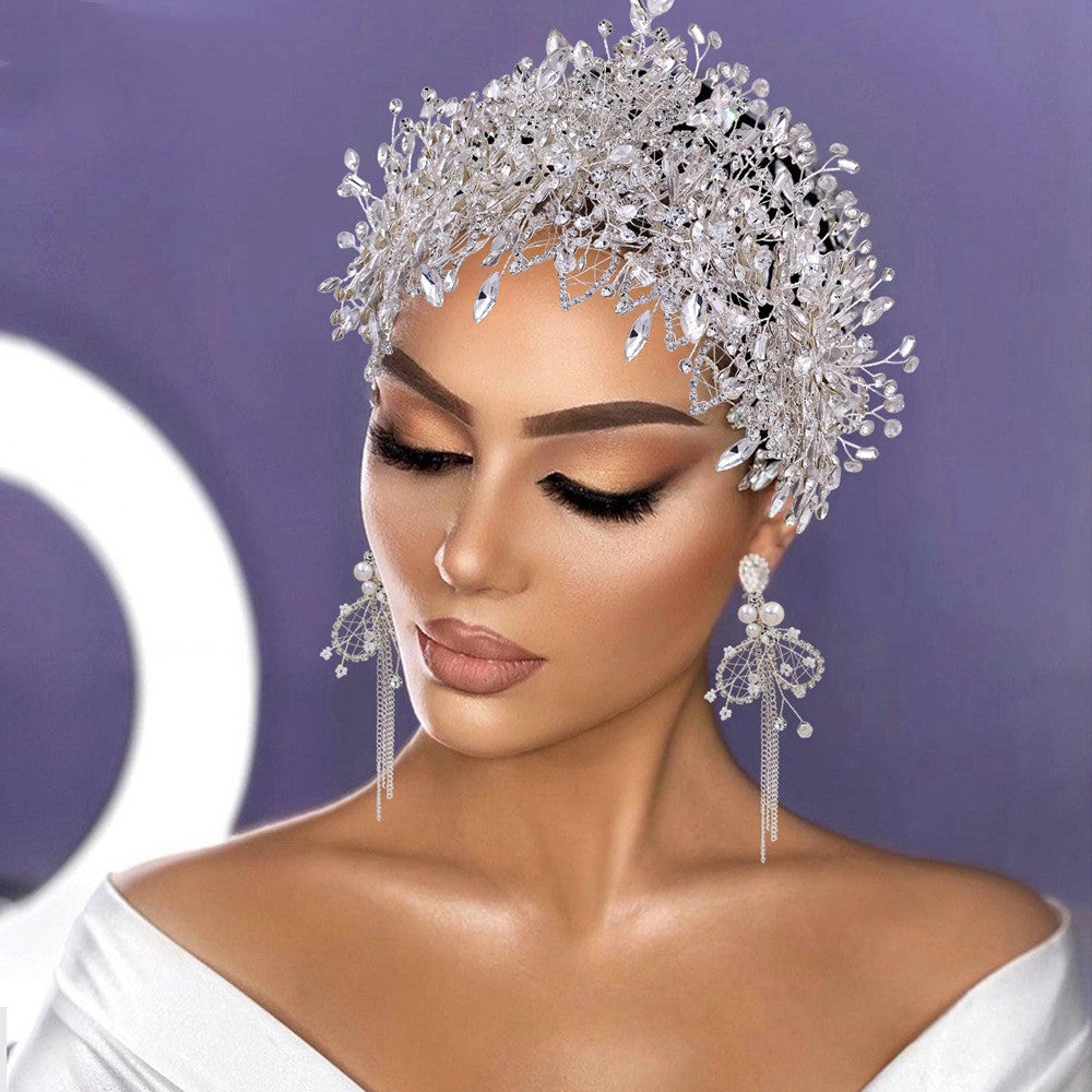 Woman wearing a sparkling silver headpiece and earrings against a purple background