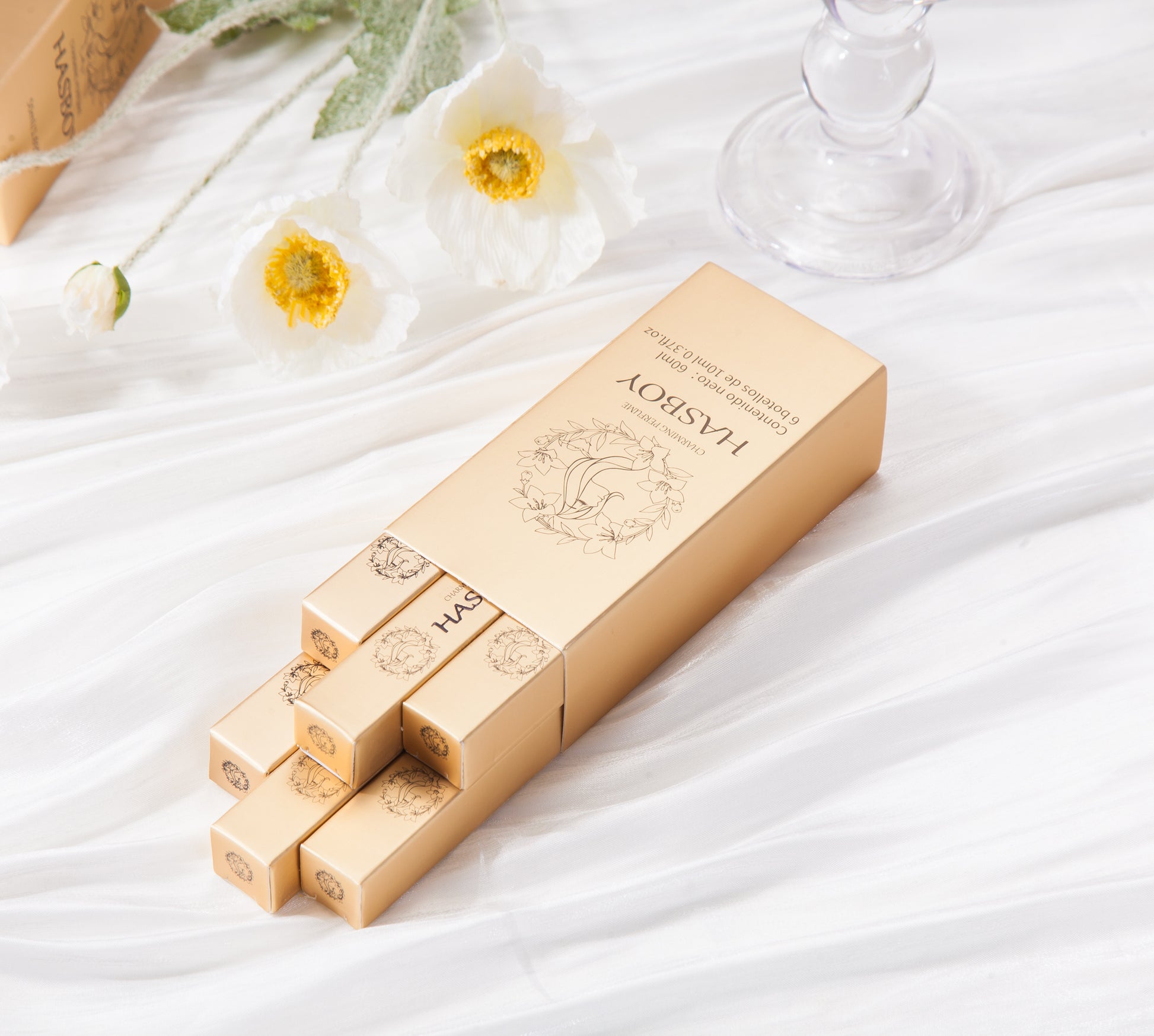 Set of gold boxes with floral design on a white fabric background
