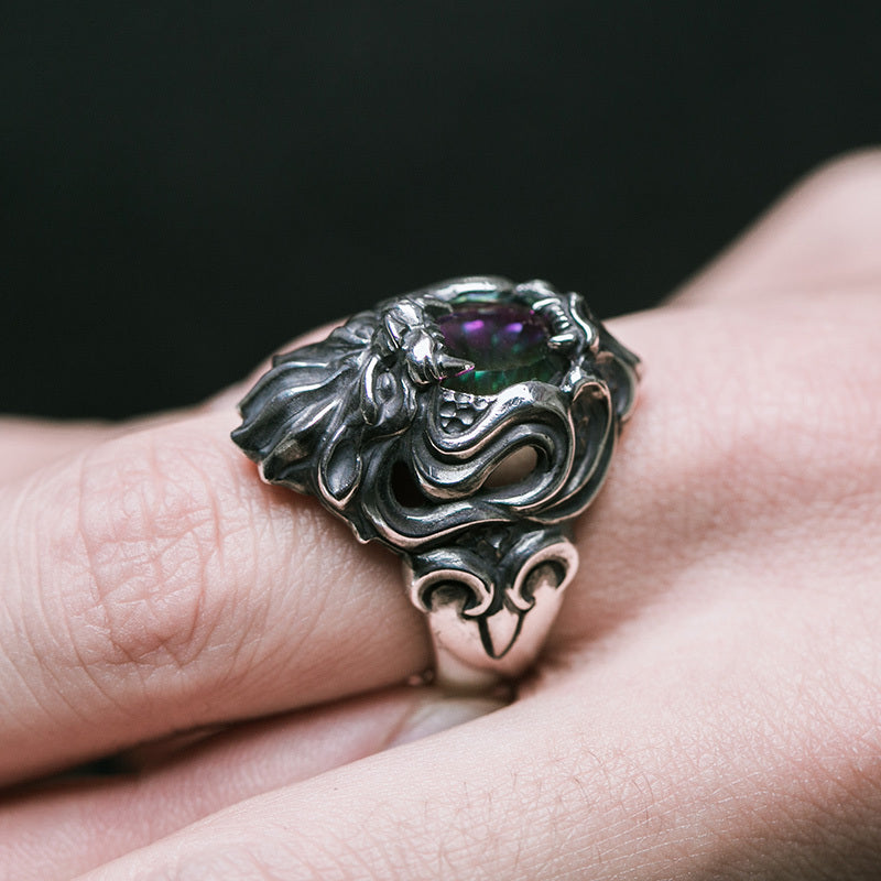 Silver ring with a purple gemstone on a finger against a dark background