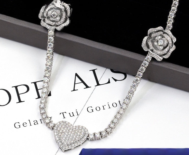 Silver necklace with floral and heart designs on a magazine background