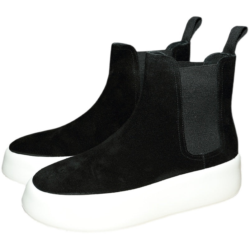 Black Chelsea boots with white soles on a white background