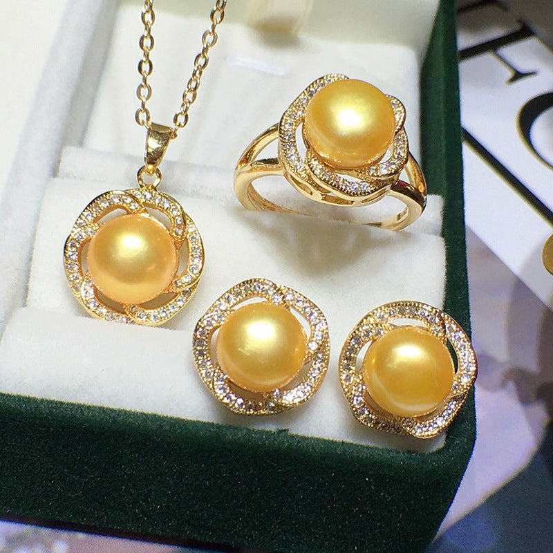 Gold jewelry set with pearls on a white cushioned surface