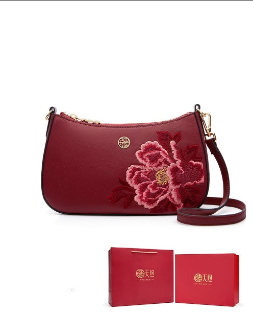 Red handbag with floral embroidery and matching box on a white background